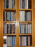 Photo of wooden shelves with multiple rows of music CDs including a Keith Jarrett box set and other artist albums.