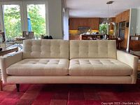 Full front view of off-white tufted sofa in living room