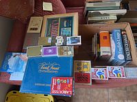 Full view of lot showing various books, card decks, language dictionaries and Trivial Pursuit game box