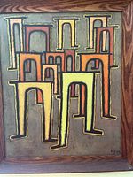 Close up of the framed print showing geometric architectural shapes in orange and yellow tones with black outlines.
