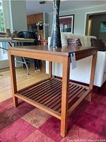 Full view of the Stickley cherry wood end table showing top surface and slatted bottom shelf in a living room setting.