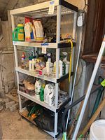 Full front angled view of tall white plastic shelving unit with assorted gardening supplies such as plant fertilizer, sprayers, and cleaning products placed on shelves.