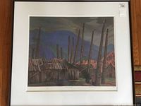 Framed print showing a village scene with tall poles under a moody sky.