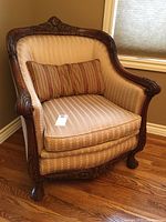 Angled front-left view showing overall shape, carved wood frame, upholstery and pillow