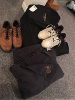 Photo showing both pairs of men's golf shoes, the black Wilson golf bag cover, and the navy blue Queens University fleece blanket on the floor.