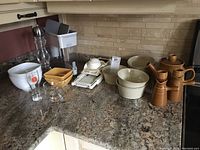 View of general kitchenware on countertop including bowls, teapot, cruets, Brita jug, mandoline, and glassware.