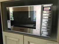 Front view of stainless steel countertop microwave oven on cabinet surface.