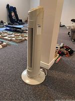 Side view of the tall cream-colored tower fan showing the grille and circular base.