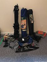 General overview of the lot showing two collapsible outdoor chairs in bags, weights, various bags, and fitness accessories.