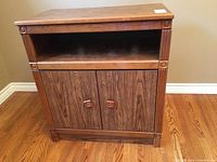 Front view of wood grain laminate TV stand showing open shelf and closed double-door cabinet.