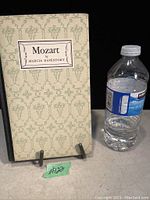 Front cover of the book showing title label and decorative pattern, with standard water bottle for scale.