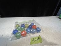 7 antique marbles in plastic zip bag, various colors and large size, on a white surface with a black background