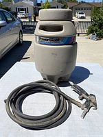 Full front view of the Campbell Hausfeld Power Blaster showing the tank with label and coiled hose attached.