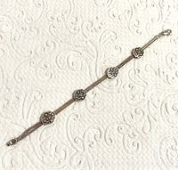 Top side view of sterling silver double strand bracelet showing textured nugget charms spaced evenly along the length against a patterned background