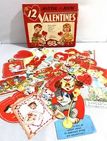 Opened red box of A-Meri-Card Valentines with assorted colorful vintage valentines and cutouts laid out