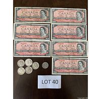 Front view of seven Canadian $2 bills from the 1954 series with visible serial numbers and one visible signature, along with six US coins including five half dollars and one smaller coin.