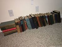 Group of about 20 vintage hardback books, mostly older yearbooks and textbooks, arranged leaning against a wall.