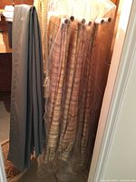 Six tartan style curtains rolled and covered in plastic hanging