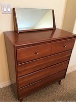 Front full view of solid maple four drawer dresser with a rectangular mirror placed on top, showing overall shape and size.