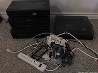 Sony audio components stacked on carpet including tuner, cassette deck, equalizer, and separate turntable to the right. Power strip and assorted cables in foreground.