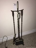 Full view of fireplace tool set on stand with poker, shovel, brush, and tongs.