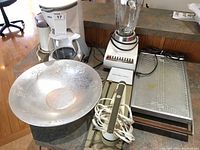 Photo showing Braun coffee grinder and 10 cup coffee maker, Sunbeam blender, Philips electric carving tool, Salton warming tray, and large aluminum bowl arranged on a counter.