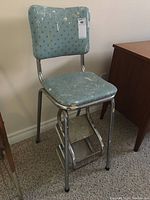 Full view of the vintage step ladder showing overall structure, metal frame, blue padded seat and backrest, and stepladder steps.
