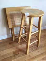 Two folding wood TV tables and one wooden stool showing wear and staining.