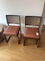 Pair of oak dining chairs with rectangular cane backs and pink upholstered seats, cane backs showing damage, upholstery worn and stained