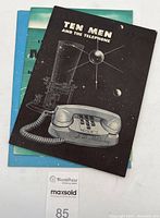 Three vintage paper booklets including 'Ten Men and the Telephone' front black cover featuring a vintage phone and satellite, 'Countdown to Tomorrow Project Echo' blue cover with earth and satellite illustration, and 'The Magic Behind Your Dial' blue cover booklet stacked behind.