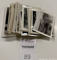 Stack of over 50 vintage black and white photographs with scalloped and straight edges shown folded through a stack with some images visible.