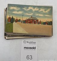 Stack of postcards showing one card on top with color image labeled 'Main Gate, Fort Devens, Mass'. Cards stacked below unidentifiable due to overlap.