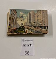 Stack of vintage postcards with the top showing a colored linen postcard of Flagler Street in Miami, Florida with vintage cars and buildings.