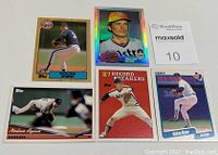 Five Nolan Ryan baseball cards from Topps and Fleer displayed flat with various pitching poses and designs, including '87 Record Breakers card and vintage style cards.