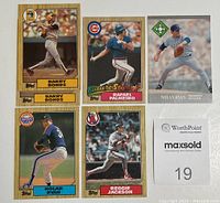 Photo of six MLB baseball cards laid out flat on a white surface, showing Barry Bonds, Rafael Palmeiro, Nolan Ryan (two cards), and Reggie Jackson cards.