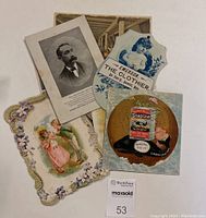 Seven pieces of Victorian advertising ephemera laid out overlapping on a white surface including Soapine advertisements and floral themed cards.