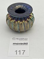 Front angle view of the ribbed iridescent glass ink well showing the flared rim and rounded body with iridescent colors.