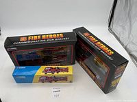 Three boxed Corgi fire truck sets arranged on table showing packaging and brand markings.