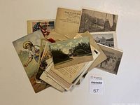 Pile of various aged paper ephemera including postcards, photographs, historical documents, and letters spread on a surface.