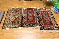 Three rugs laid on floor showing two matching smaller rugs and one distinct larger rug.