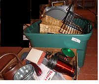 Photo showing green plastic tote containing woven baskets, metal chip and dip server, and various kitchen items