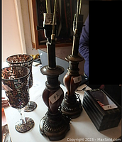 Photo shows two electric lamps without shades with dark wood bases and metal detailing, two cut glass mosaic candle holders next to them, and a boxed night light to the side.