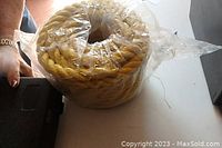 Entire packaged coil of yellow twisted polyester rope.