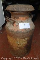 Full view of a large, rusted antique metal milk can showing lid and two pouring spouts