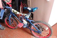 16-inch blue Avengers-themed children's bicycle with training wheels, red pedals and red rims, featuring Avengers character graphics on the frame.