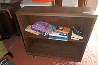 Full view of wooden bookshelf with books on upper and middle shelves, showing cabinet's finish and book condition.