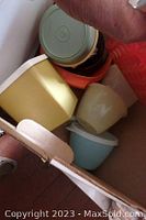 Photo of a box containing vintage Tupperware creamers, tumblers and storage containers in pastel colors.