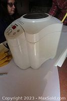 Front view of white Breadman breadmaker showing control panel on top front with buttons and display.