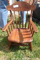 Front view of the child size solid wood rocking chair showing carved top backrest and spindle details.