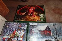 Four Cobble Hill jigsaw puzzles shown together with dragon, birds with puppy, and barn designs visible.